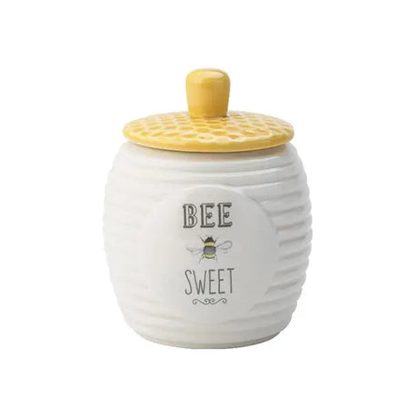 A small white ceramic pot with the words Bee Sweet on the front and a yellow honeycomb embossed lid