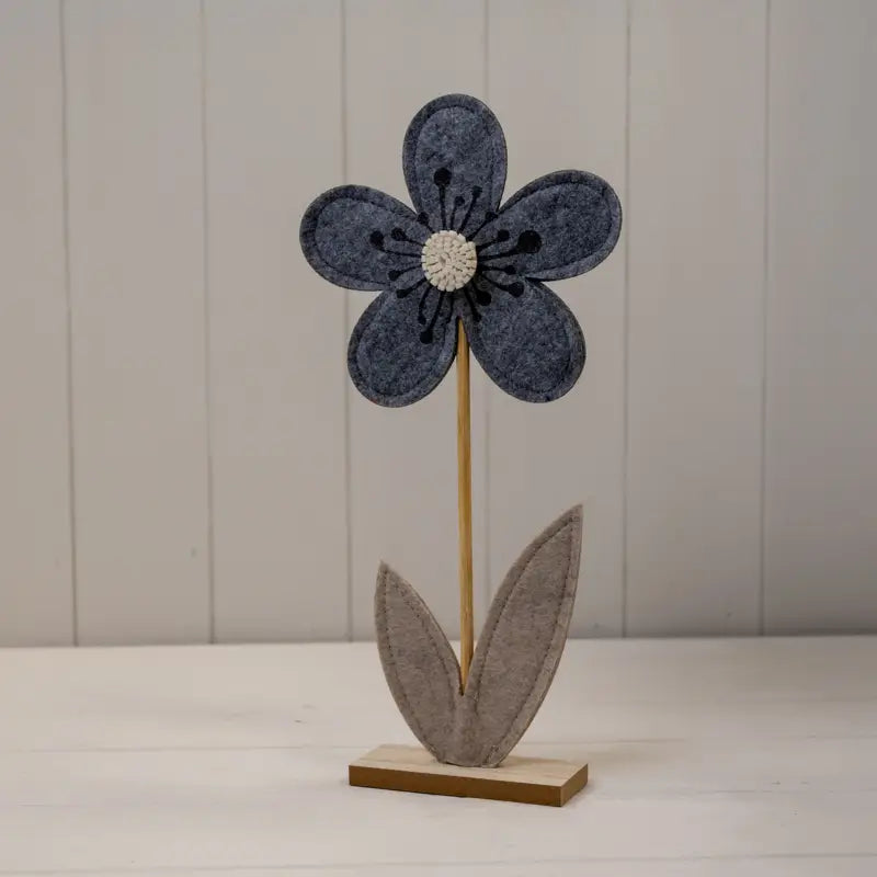 Decorative flower with a blue petal and brown stem on a white surface.