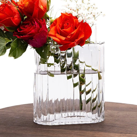 Clear glass handbag vase with red roses on a wooden round tray