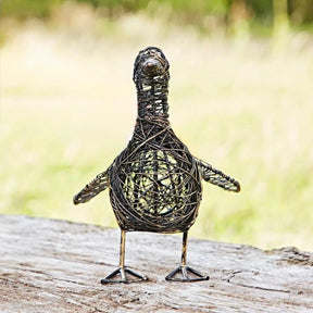 Wire bird sculpture on a wooden log with a blurred natural background