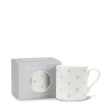 A white fine bone china mug with a pattern of small gray hearts, shown next to its light gray packaging box on a white background.
