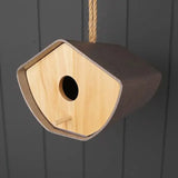 Wooden birdhouse with a dark brown frame and light wood interior on a dark gray background