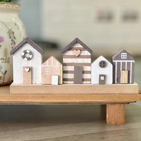 A wooden ornament depicting a row seaside houses, placed on a raised wooden tray