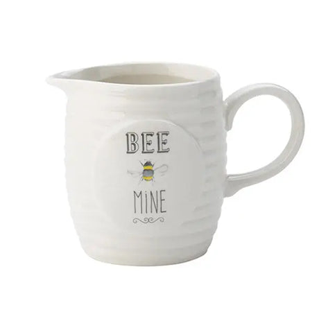 A white ceramic creamer jug with the words Bee Mine on the front