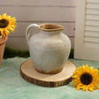 A Grey Ceramic pitcher on a wooden board with sunflowers on either side