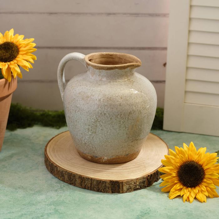 A Grey Ceramic pitcher on a wooden board with sunflowers on either side
