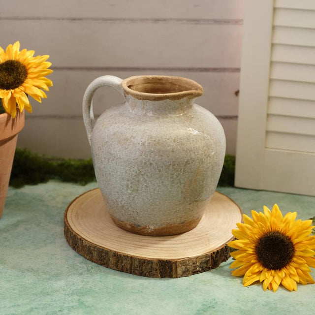 A Grey Ceramic pitcher on a wooden board with sunflowers on either side