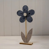 Decorative flower with a blue petal and brown stem on a white surface.