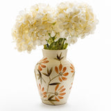 A cream-coloured ceramic vase with a floral pattern of orange and brown flowers, filled with white artificial hydrangea blooms, set against a plain white background.