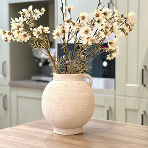White terracotta vase with white flowers on a kitchen counter