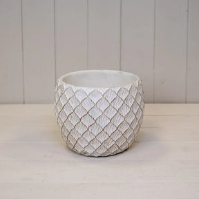 Decorative textured pot on a white surface with a light gray background