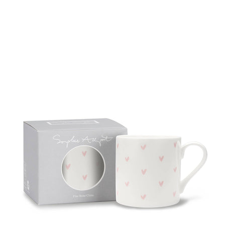 White mug with pink heart patterns in a branded box on a white background