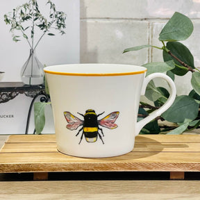 Bone China Mug featuring Bella the Bee, placed on a wooden board